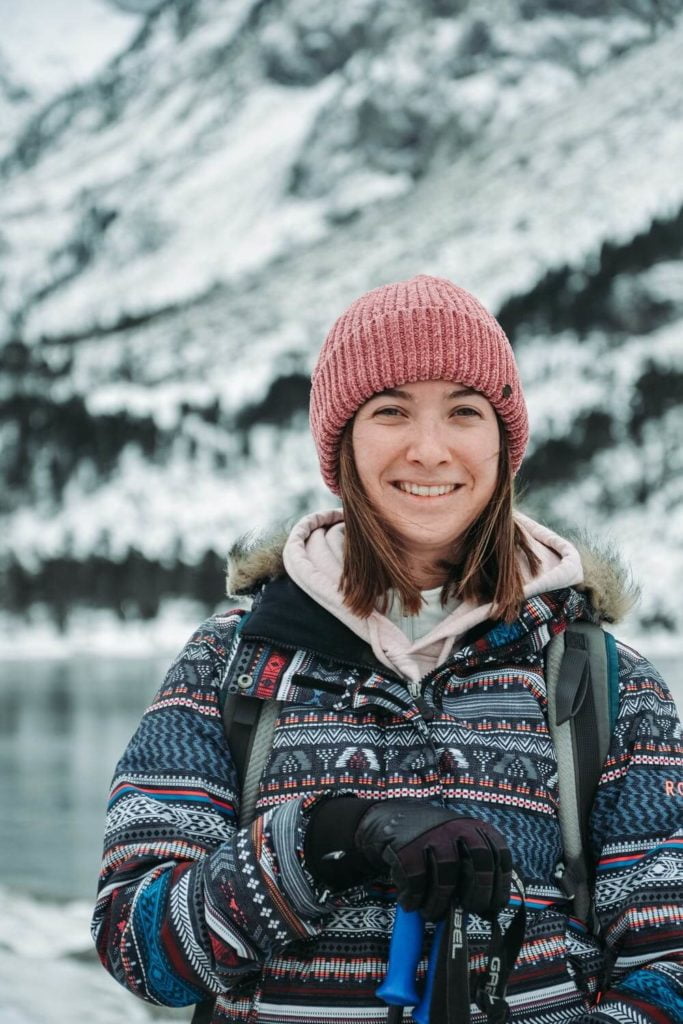 a person wearing a pink hat and backpack in front of a mountain